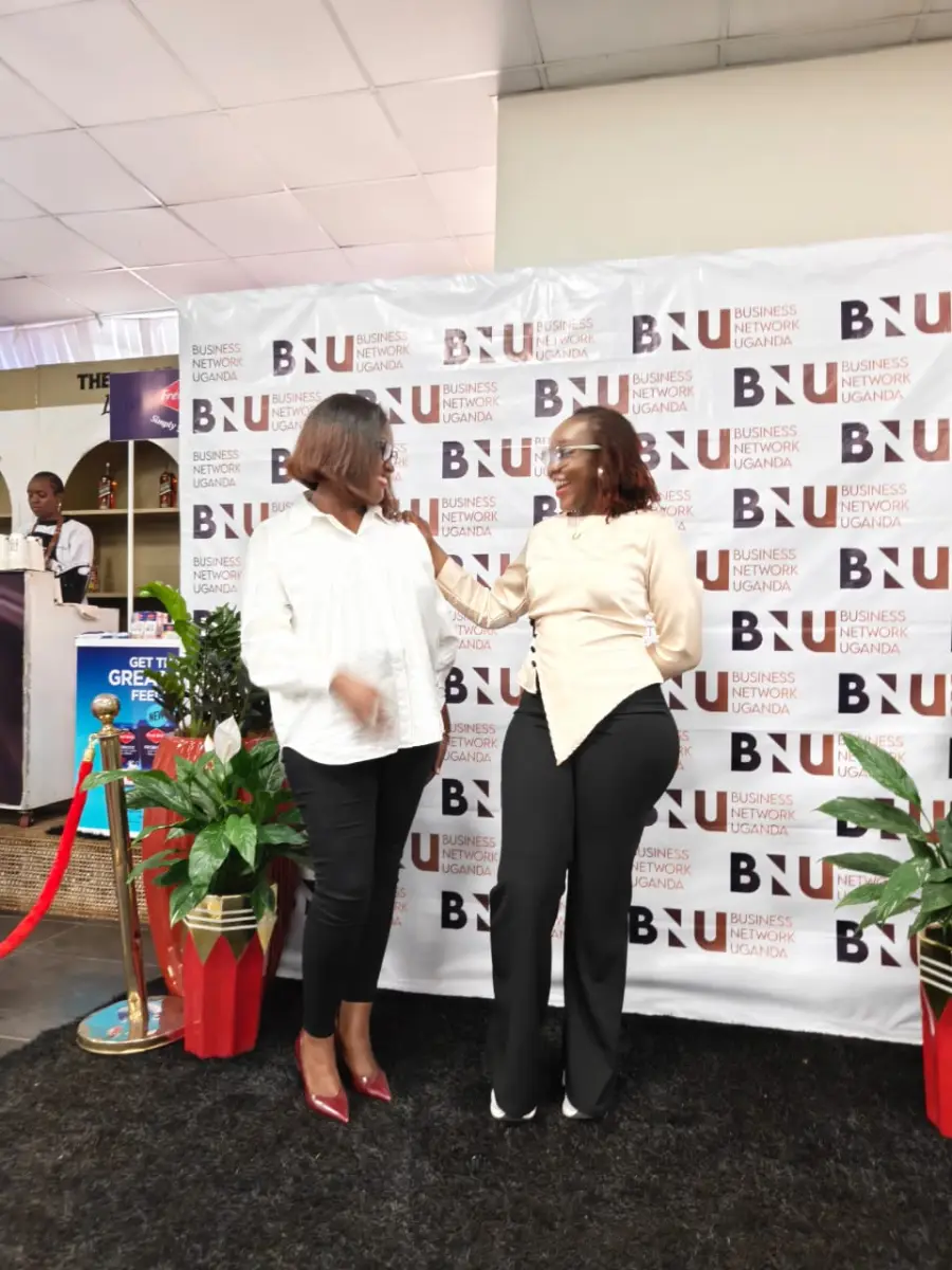 Two attendees sharing a joyful moment in front of the BNU Launch photo wall.